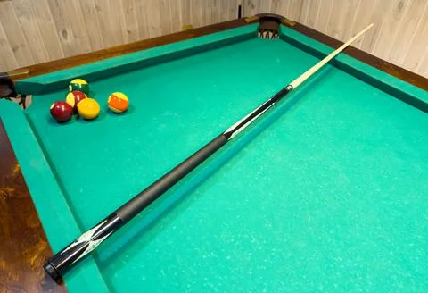 A pool table with a black pool cue and three balls on it Stock Photos