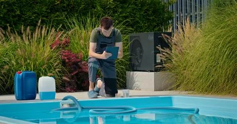 Pool technician checking data on a tablet beside a swimming pool with chemical Foto stock