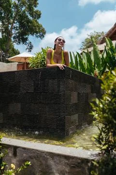 From the pool through his side peeps a beautiful brunette in sunglasses against Stock Photos