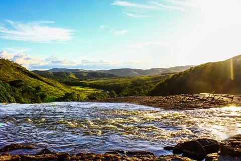 Pool of water high up between mountains full of plants while the sun sets Stock Photos