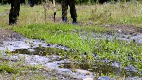 A pool of water rain mud two soldiers of military cadets stand with shovels Stock Footage 116467918
