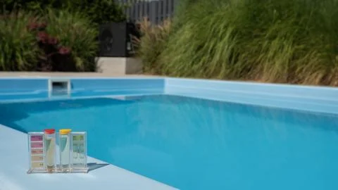 A pool water testing kit displaying pH and chlorine levels is set on the pool's 库存照片