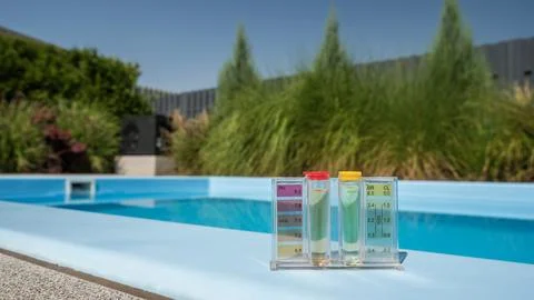A pool water testing kit with pH and chlorine levels is placed on the pool's Foto stock