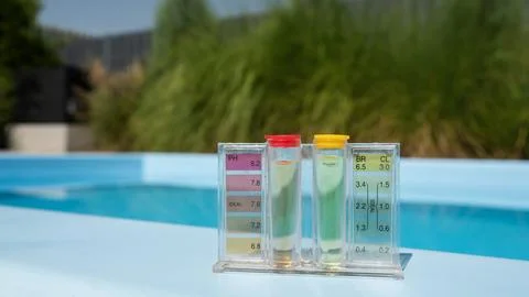 A pool water testing kit showing pH and chlorine levels is placed on the pool's 库存照片