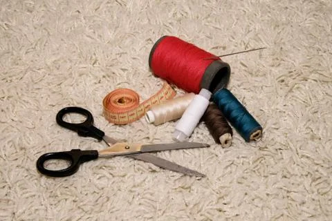 Pools of different colors of thread, needle, meter and scissors lie on a whit Stock Photos