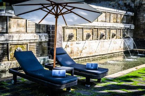 Poolside and beach side lounge chairs ad lounge beds with sun umbrellas in a  Stock Photos