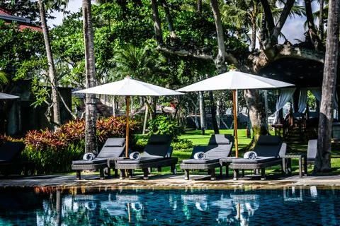 Poolside and beach side lounge chairs ad lounge beds with sun umbrellas in a  Stock Photos