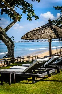 Poolside and beach side lounge chairs ad lounge beds with sun umbrellas in a  Stock Photos