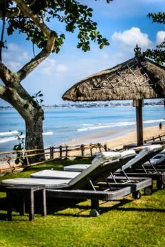 Poolside and beach side lounge chairs ad lounge beds with sun umbrellas in a  Stock Photos