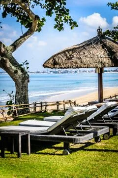 Poolside and beach side lounge chairs ad lounge beds with sun umbrellas in a  Stock Photos