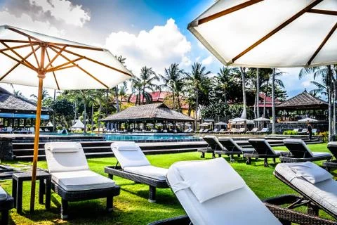 Poolside and beach side lounge chairs ad lounge beds with sun umbrellas in a  Stock Photos