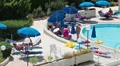 Poolside area with resting and sunbathing people near swimming pool HD Footage