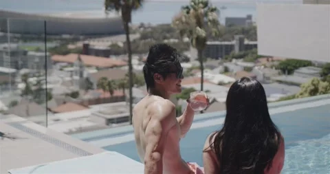 Poolside couple, man wearing sunglasses reacting to woman and raising round Stock-Footage 336897863