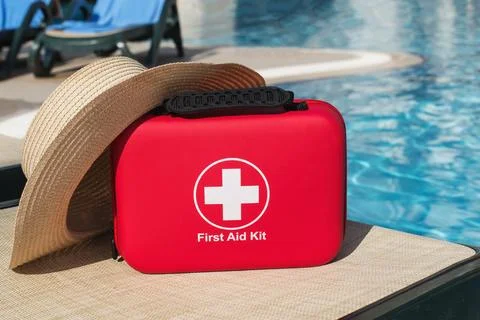 Poolside first aid kit with summer hat near resort water, vacation safety con Fotos Stock
