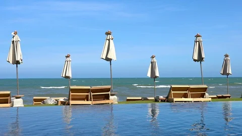 Poolside lounge with Deck chairs, Parasols tables and view on the sea Stock Footage 111891936