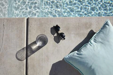 Poolside Relaxation Setup with Pillow, Sunglasses, and Water Stock Photos