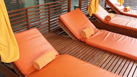 Poolside Sun lounger with Orange colored cushion and towels Stock Footage 74253960