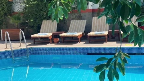 Poolside view with lounge chairs and blue pool water. Stock Footage 336904658