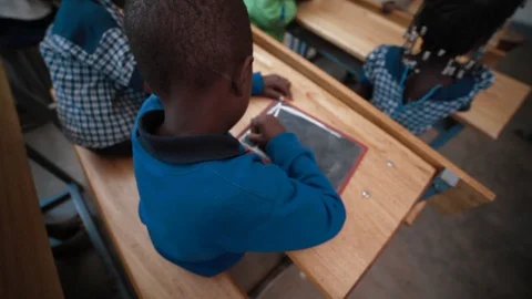 Poor african child writes at school in his classroom Stock Footage 126933664