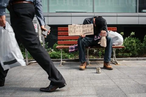 Poor and drunk man is sitting on bench and holding a cardboard which says Stock Photos