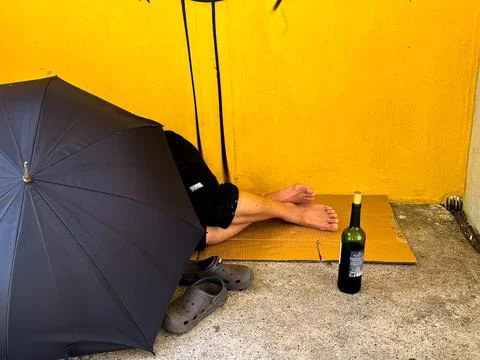 Poor and drunk man sleeping on behind the umbrella Stock Photos