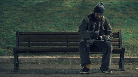 Poor beggar sit on bench at night, counting his alms 스톡 동영상 83971590