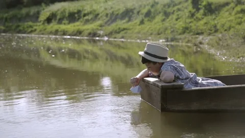 The poor boy in the boat, playing with paper boat 動画素材 76181455
