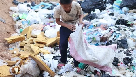 A poor boy collecting garbage waste from a landfill site in the outskirts ... Stock Footage 336937342