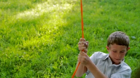 Poor boy riding a swing from a tire, beautifully painted in the garden against a Stockbeeldmateriaal 78060826