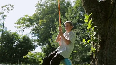 Poor boy swinging on a car tire Stock Footage 78024016