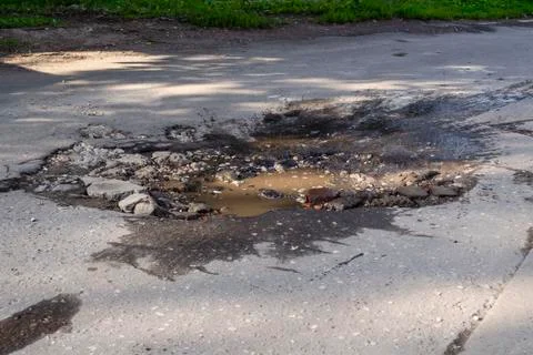 Poor condition of the road surface. Hole in the asphalt, risk of movement by Stock Photos
