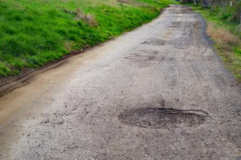 Poor condition of the road surface. Spring season. Hole in the asphalt Stock Photos