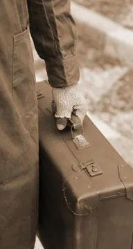 Poor immigrant with old leather suitcase and broken gloves during the trip ab Foto stock
