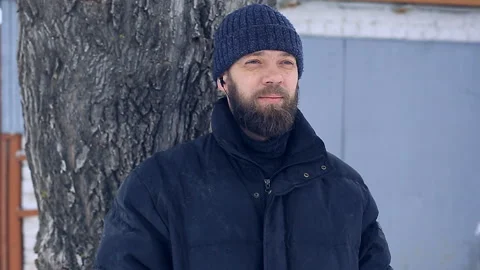 Poor man with a beard on a winter day raises his thumbs up and smiles Stock Footage 87642540