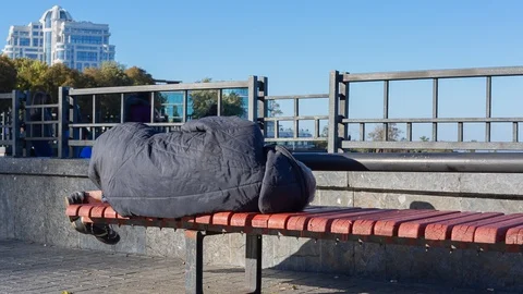Poor man laying on the bench in city park 2 Stock Footage 128934683