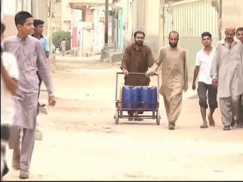 Poor man pushing heavy cart of water drums during water shortage Stock Footage 78695532