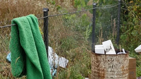 Poor people warming near fire trash barrel and drink vodka Stock Footage