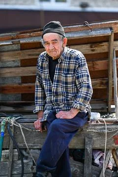 Poor russian 77 years old elderly man sits outdoors looking into camera sho.. Stock Photos