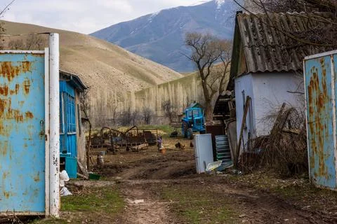 Poor rustic backyard with old blue tractor with dirt road between houses Stock Photos