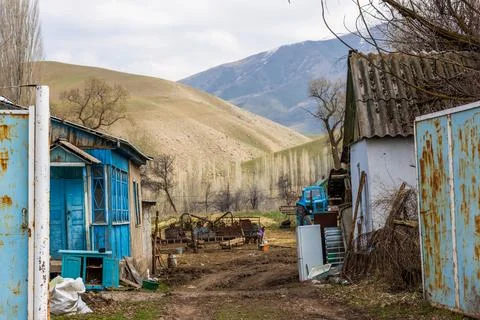 Poor rustic backyard with old blue tractor with dirt road between houses Stock Photos
