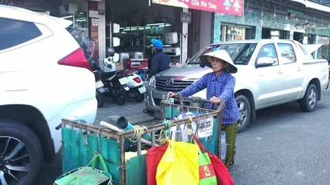A poor senior lady pushing her shabby cart on the street of Da Nang Stock Footage 146766497