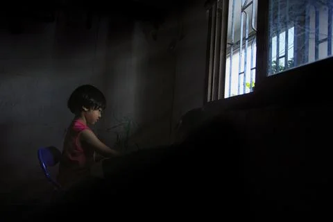 Poor students are doing their homework using the lights from the windows beca Stock Photos