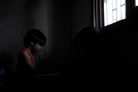 Poor students are doing their homework using the lights from the windows beca Stock Photos