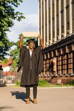 Poor unemployed black guy standing with upraised empty cardboard poster on Stock Photos