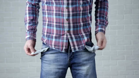 Poor young man in checkered shirt and jeans showing empty pockets Stock Footage 120865424