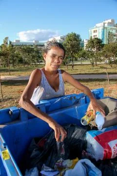 A poor young mother digging through the Trash Foto stock