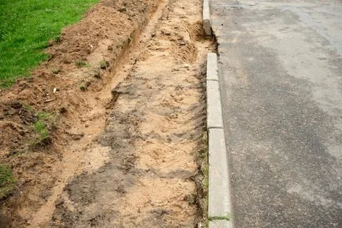 Poorly executed road repairs. replacing the old curb stone with a new one Stock Photos