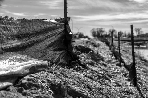 Poorly maintained silt fence at a construction site with exposed dirt piled Foto stock