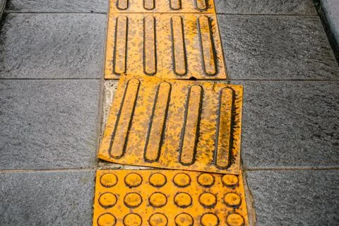 Poorly Maintained Tactile Paving on Grey Pedestrian Sidewalk Foto stock