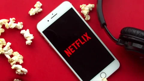 Pop Corn falling on an iPhone Plus with the Netflix logo a red background Stock Footage 131564430